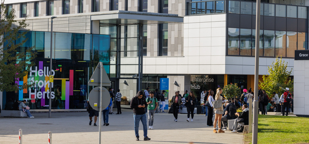People walking outside on campus. The Enterprise Hub can be seen in the background.